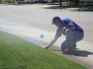 checking on a sprayer head during a regular sprinkler repair in Boca Raton, FL